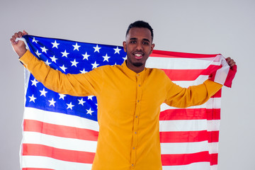 african american man looking at camera and proudly holding american flag at studio