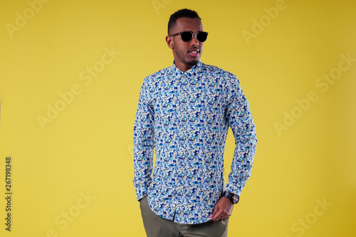 Fotomural Portrait of attractive young african man sunglasses on yellow wall