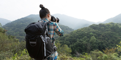 woman photographer taking photo on morning mountain forest