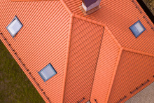 Aerial Top View Of House Metal Shingle Roof, Brick Chimneys And Small Plastic Attic Windows. Roofing, Repair And Renovation Work.
