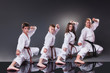 Group of young karate players doing kata on the gray background