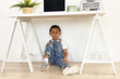 © Anatoliy Karlyuk - People, children, lifestyle and interior design concept. Horizontal view of cool fashionable African schoolboy wearing stylish clothes sitting confidently on floor under white table with laptop
