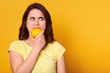 © sementsova321 - Natural vitamins and healthy food concept. Indoor shot of young brunette woman bits lemon with discontented facial expession, looking angrily aside, copy space for your promotion text or advertisment.