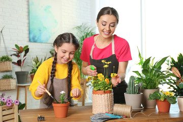 Canvas Print - Mother and daughter taking care of potted plants at home