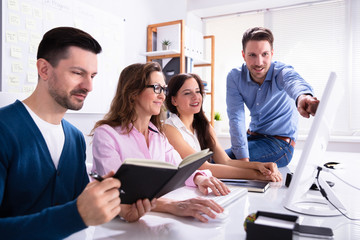 businessman showing information on computer to colleagues