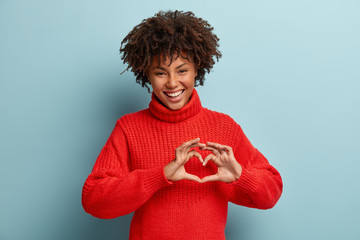 portrait of lovely female model makes heart gesture, says be my valentine, demonstrates love sign, h