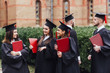 © Тарас Нагирняк - Portrait of graduate school kids standing with degree scroll in campus at school