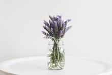 Close Up Of Lavender In Glass Jar On Small Table Against Neutral Wall Background - Matte Filter Effect And Selective Focus