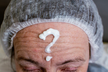 Portrait of middle aged woman with a towel on her head applying cream on her face