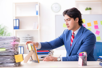 Young male handsome employee in conflicting priorities concept 