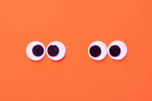 Googly Eyes: One Pair Strabismus And Squint Mad Googly Eyes And One Pair Normal Funny Eyes Next To Each Other On Orange Background.