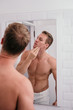 © Odua Images - Handsome athletic men shirtless at front reflection the mirror in the bathroom