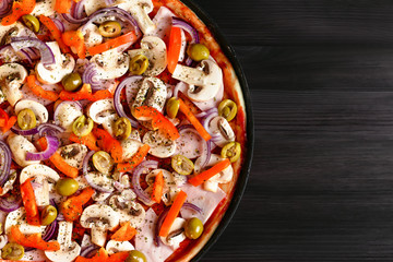 Italian pizza closeup on dark wooden background with mushrooms and vegetables, top view