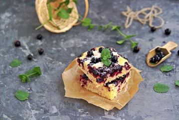 Wall Mural - Sweet sliced cake with cornmeal and black currant. Decorated with fresh mint, powdered sugar and berries of frozen black currant.