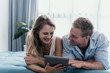 © Odua Images - Happy couple enjoy using tablet for browsing while lying in the bedroom