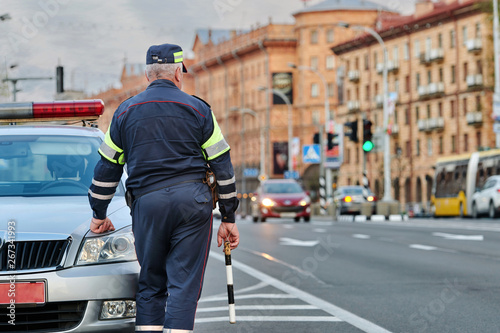 Traffic security officer in blue uniform. Road police man control and  prevention of violations on the road. Traffic cop with striped police stick  checking and directing trafficc. Police patrol car Stock Photo
