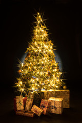 Wall Mural - Gifts and golden Christmas tree bokeh in a black background