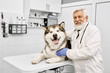 © serhiibobyk - Elderly vet doctor posing with malamute in medical cabinet.