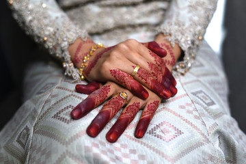 close up of a malay bride hand with henna tattoo and gold rings her wedding day.bride wearing songket fabric, malay tradition dress. Concept of tradition and culture