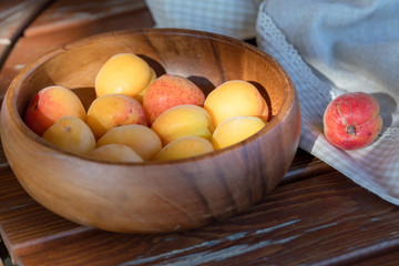 The ripe apricots, juicy fresh yellow with red outflow, which grew on the Azerbaijani earth in a wooden cup in beams of the sunset sun. Macro.