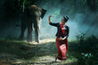 Beautiful young Thai woman northeast style is enjoy dancing and playing with elephant in the jungle in Surin, Thailand.