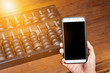 Smartphone with The antique  black abacus on wooden table