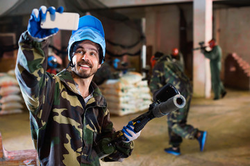 Wall Mural - Man in blue mask is making selfie on battlefield