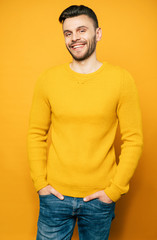 Close up portrait of happy handsome man in yellow is posing over orange background