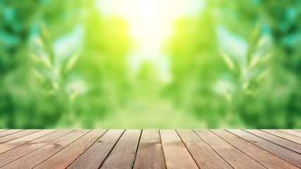 Empty wooden table, natural blurred greens on the background, the sun's rays