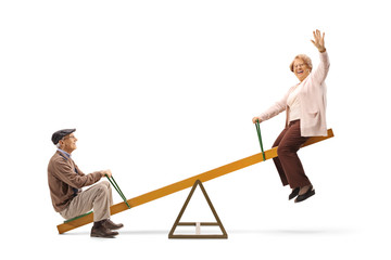 Wall Mural - Senior man and woman waving and sitting on a seesaw