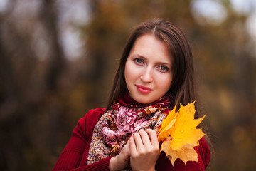 beautiful young woman with yellow maple leaves in hands