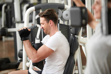 Wall Mural - Handsome muscular man in gym doing exercises. Caucasian male taking efforts to finish set on chest press. Regular sport training for perfect shape.