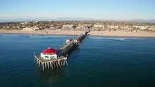Aerial View Over Pier And Beach In Huntington Beach, Orange County California On A Sunny Blue Sky Summer Day With People On The Coast Enjoying Vacation.