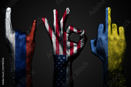 Fotografía a set of three hands with a painted flag of Ukraine, Russia and USA show middle finger, goat and Okay, a sign of aggression, protest and approval on a dark background