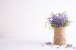 lovely purple flower in sack vase on white wooden table.