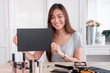 © weedezign - Asian young female blogger giveaway gift fan following channel while recording vlog video with makeup cosmetic at home online influencer concept.live streaming viral.mock up blackboard for your design