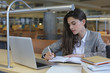 © ty - Portrait of a pretty female student with laptop in library.