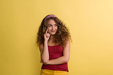 Wall Mural - Portrait of a young woman with headband in a studio on a yellow background.