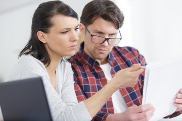 Wall Mural - couple sitting on couch calculating bills