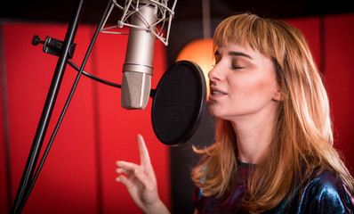 Wall Mural - Female singer with microphone recording a song in music studio