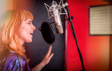 Wall Mural - Female singer with microphone recording a song in music studio