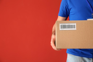 Delivery man with box on color background, closeup