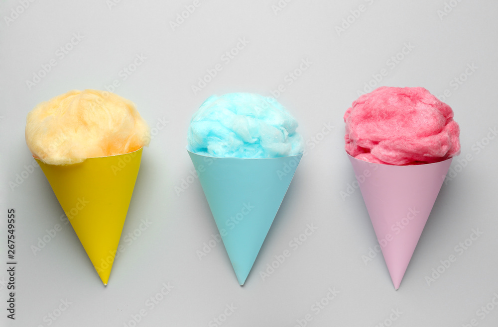 Cones with tasty cotton candy on grey background