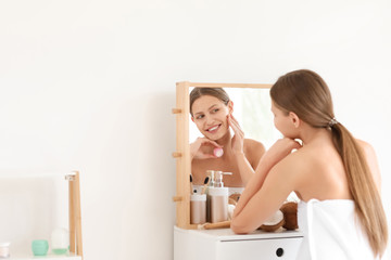 Sticker - Beautiful young woman applying cream with coconut extract at home