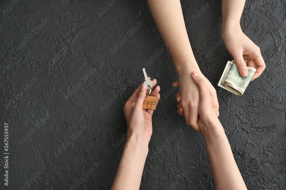 Real estate agent and buyer shaking hands on dark background, top view