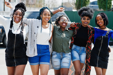 Group of five african american woman walking on road together against suv car on parking.