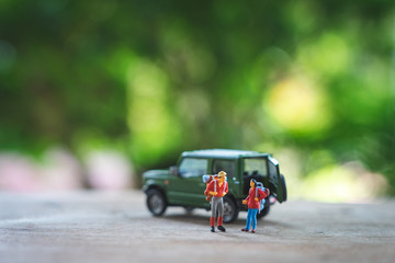 Miniature 2 people standing travel planner with yellow toy car model as background travel concept with copy space.