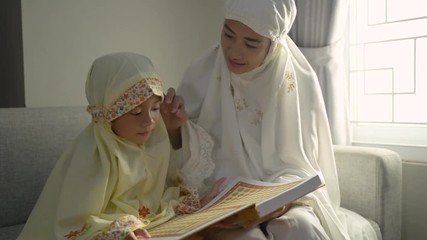 Wall Mural - muslim parent and daughter reading quran after praying together