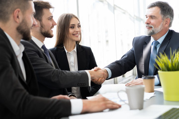 Canvas Print - Business people shaking hands while working in the creative office