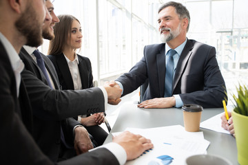 Canvas Print - Business people shaking hands while working in the creative office